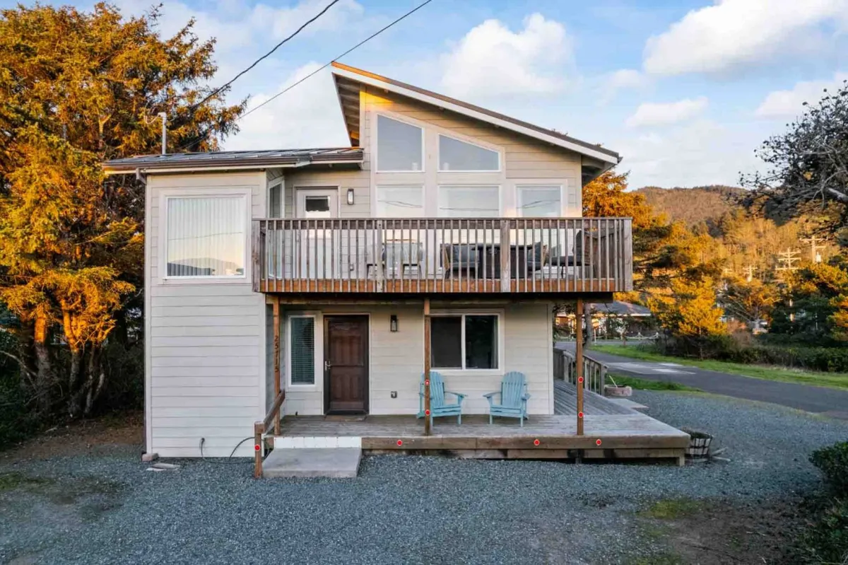 A spacious wooden balcony furnished with classic Adirondack chairs and bordered by large windows. The deck overlooks a scenic expanse, inviting guests to relax, take in the view, and enjoy outdoor dining or gatherings—ideal for hosting barbecues or savoring meals with panoramic vistas.